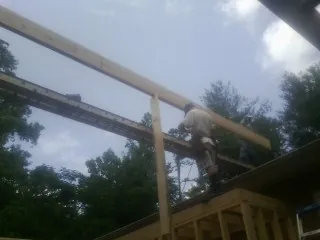 Carpenter setting a ridge beam over a new addition frame — Ice Dam Removal by Roofing Brothers in Opelousas