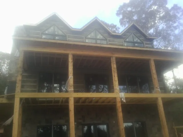 Dormers and porch framing on a large log home under construction — Roof Coating work by our crew in Opelousas