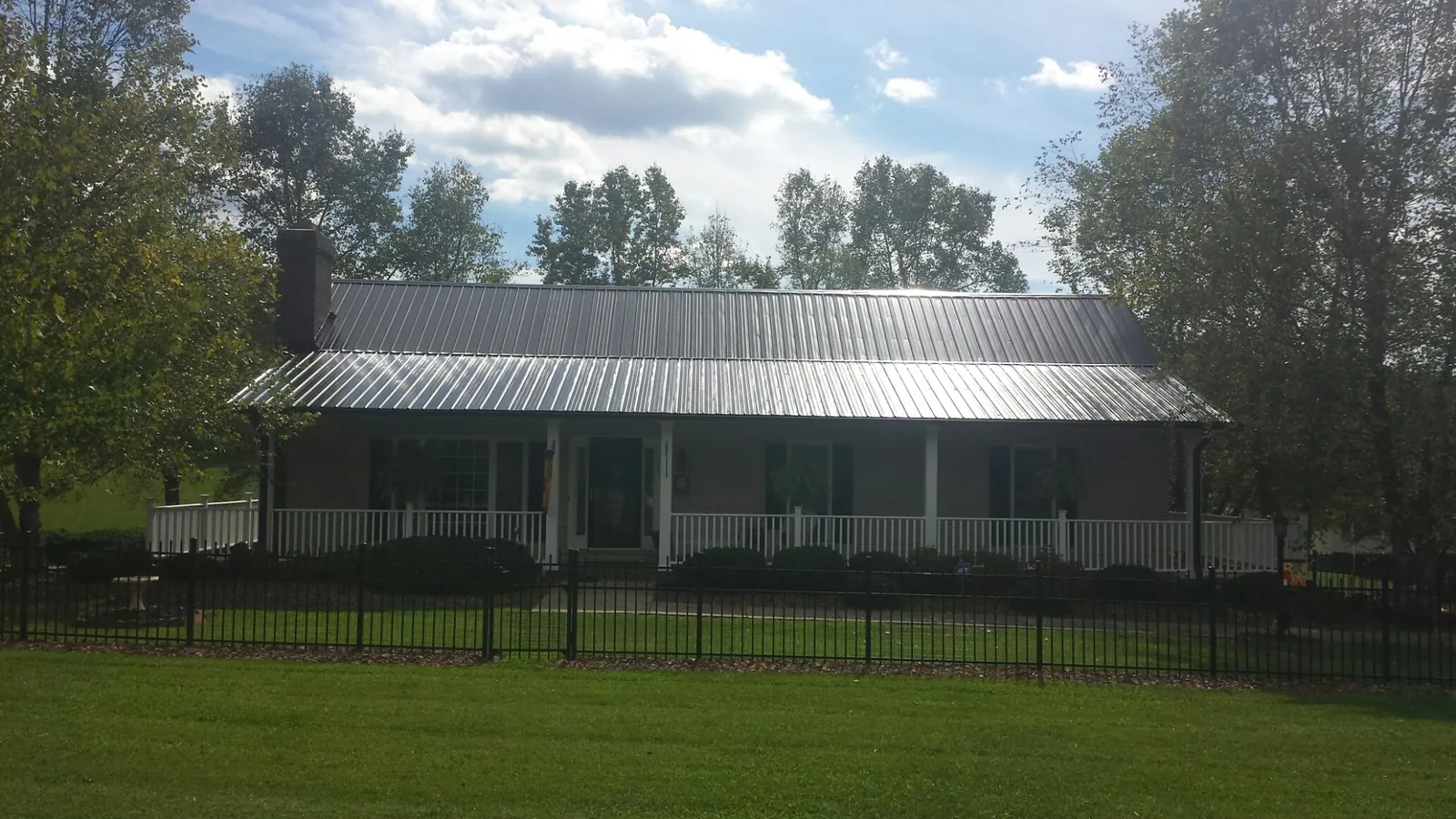 Gray metal roof on a brick ranch with a full width front porch — Gutter Guard Installation work by our crew in Opelousas