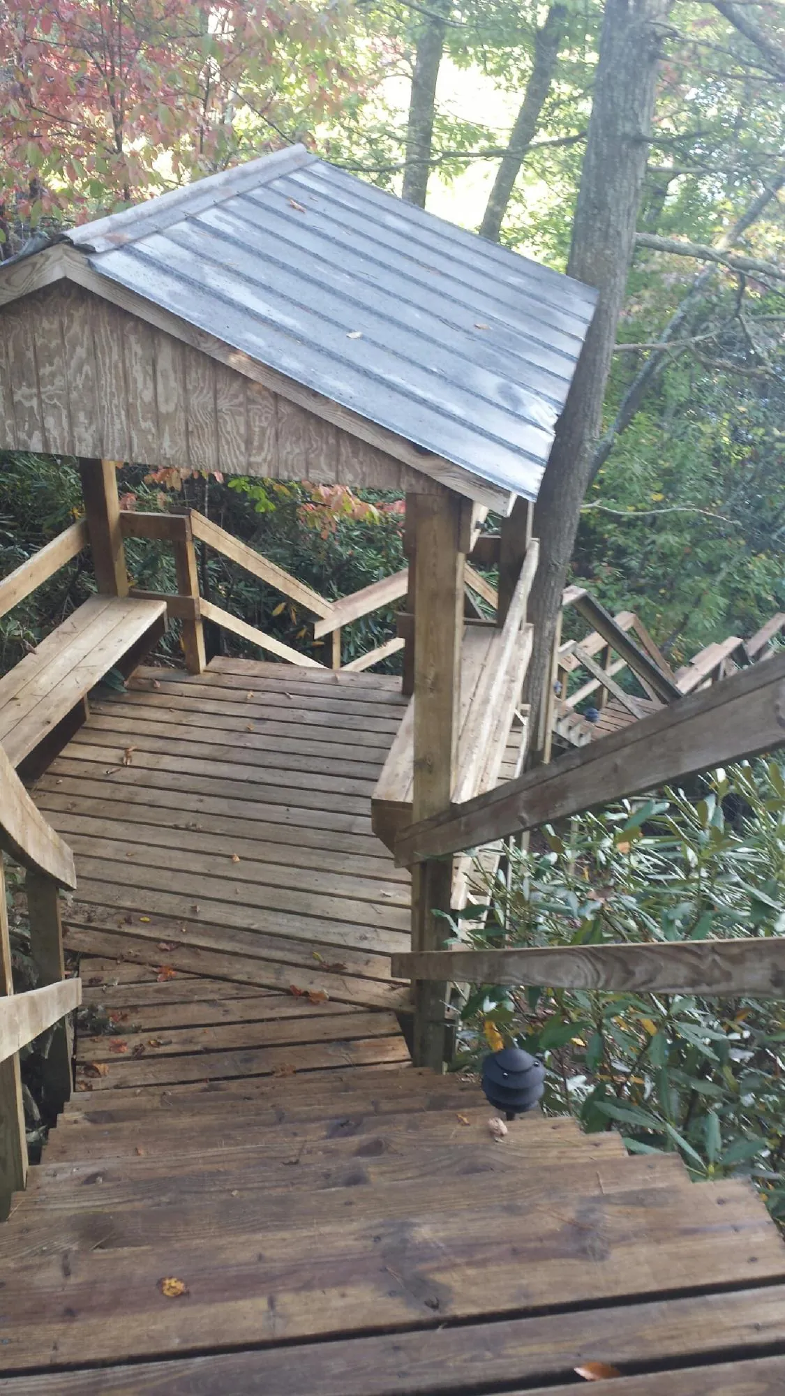 Metal roofed shelter over wooden steps on a wooded walkway — Skylight Repair & Installation work by our crew in Opelousas